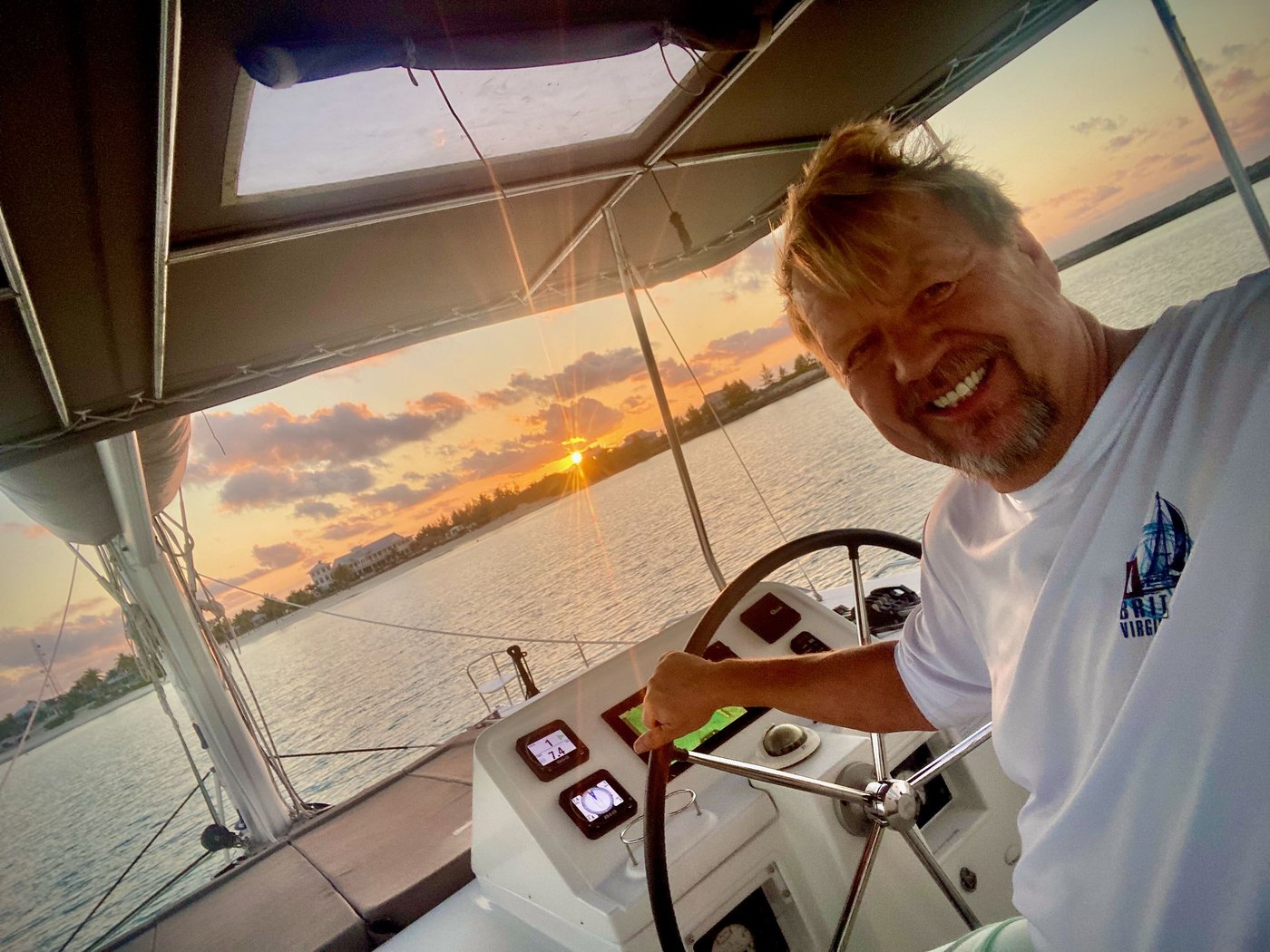 Daniel Garth at the helm of a sailboat at sunset